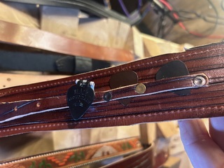 Handmade leather guitar strap holding guitar picks